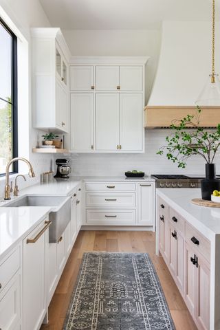 A white kitchen with a printed rug along the pathway