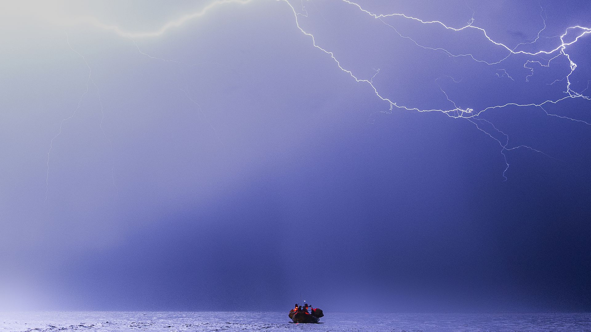 
                                Lightning strikes overhead as members of the SOS Mediterranee rescue ship "Ocean Viking" conduct an exercise in the Mediterranean Sea
                            