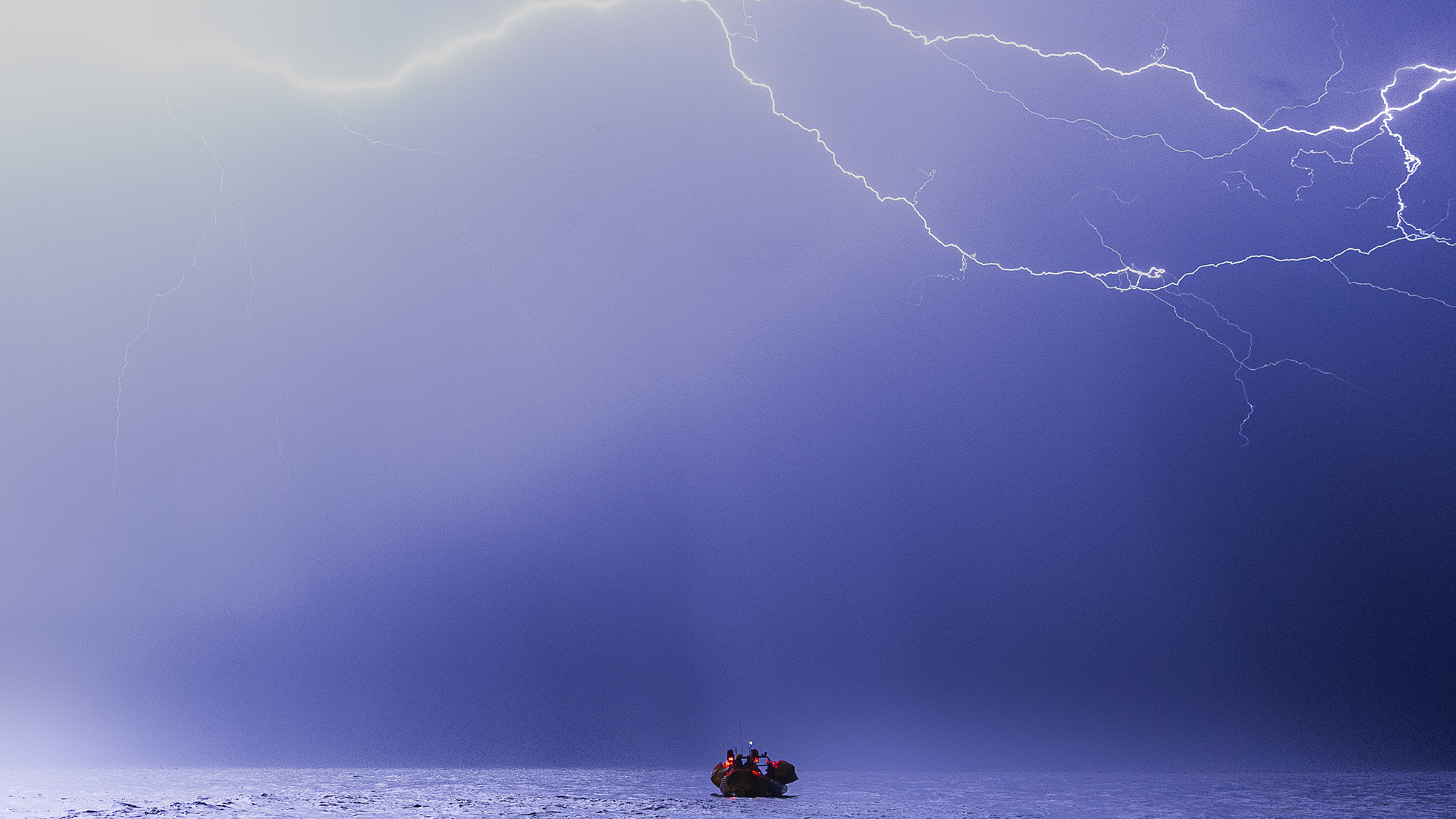 Lightning strikes overhead as members of the SOS Mediterranee rescue ship "Ocean Viking" conduct an exercise in the Mediterranean Sea