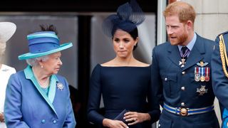 Queen Elizabeth II, Meghan, Duchess of Sussex and Prince Harry, Duke of Sussex watch a flypast to mark the centenary of the Royal Air Force