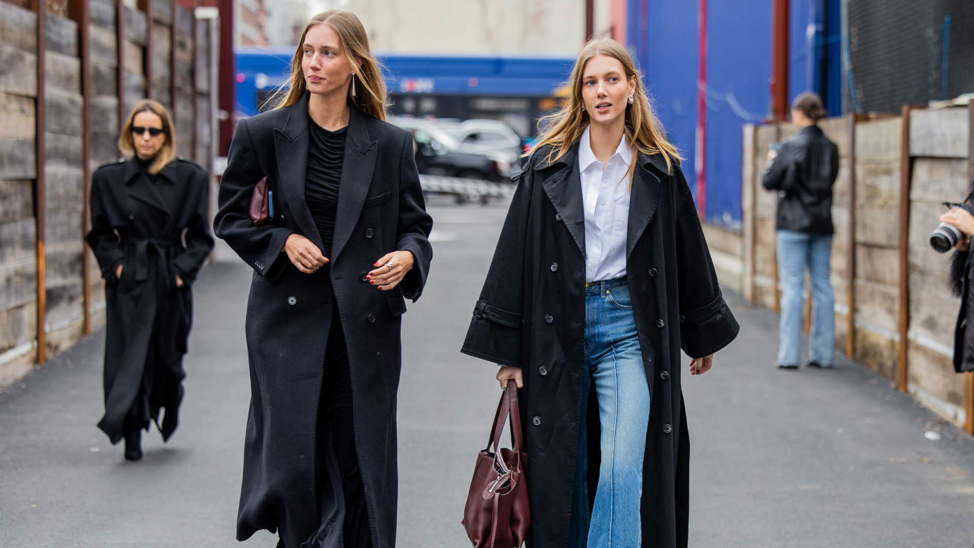 Twins Amalie &amp; Cecilie Moosgaard wearing black trench coat, denim jeans, white button shirt outside Ulla Johnson on February 11, 2024 in New York City.