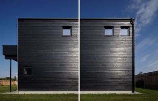 The exterior of a residential home clad in black timber planks surrounded by grey concrete and green lawn