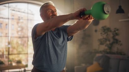 A man performing a kettlebell swing at home