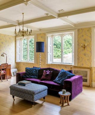 living area with yellow wallpaper and purple sofa