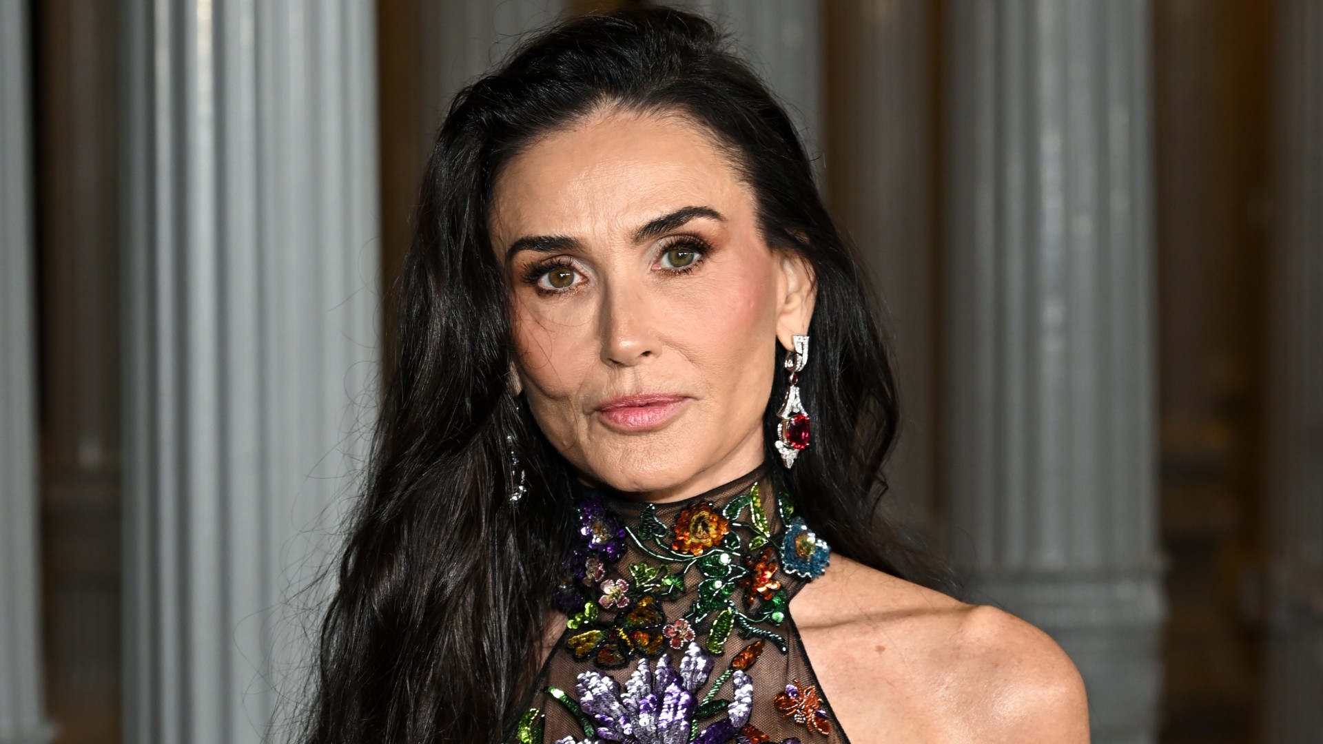 a close up photo of a white woman with long, dark hair posing for paparazzi at a red carpet event