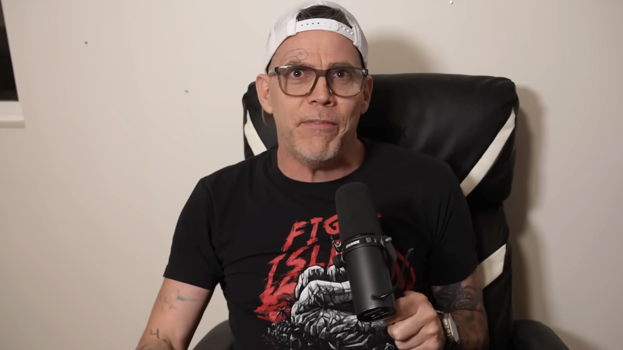Steve-O holds a mic and hosts his podcast, Wild Ride with Steve-O.