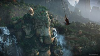 Chloe swings from a grappling hook in front of a stone carving of Ganesh in Uncharted: The Lost Legacy