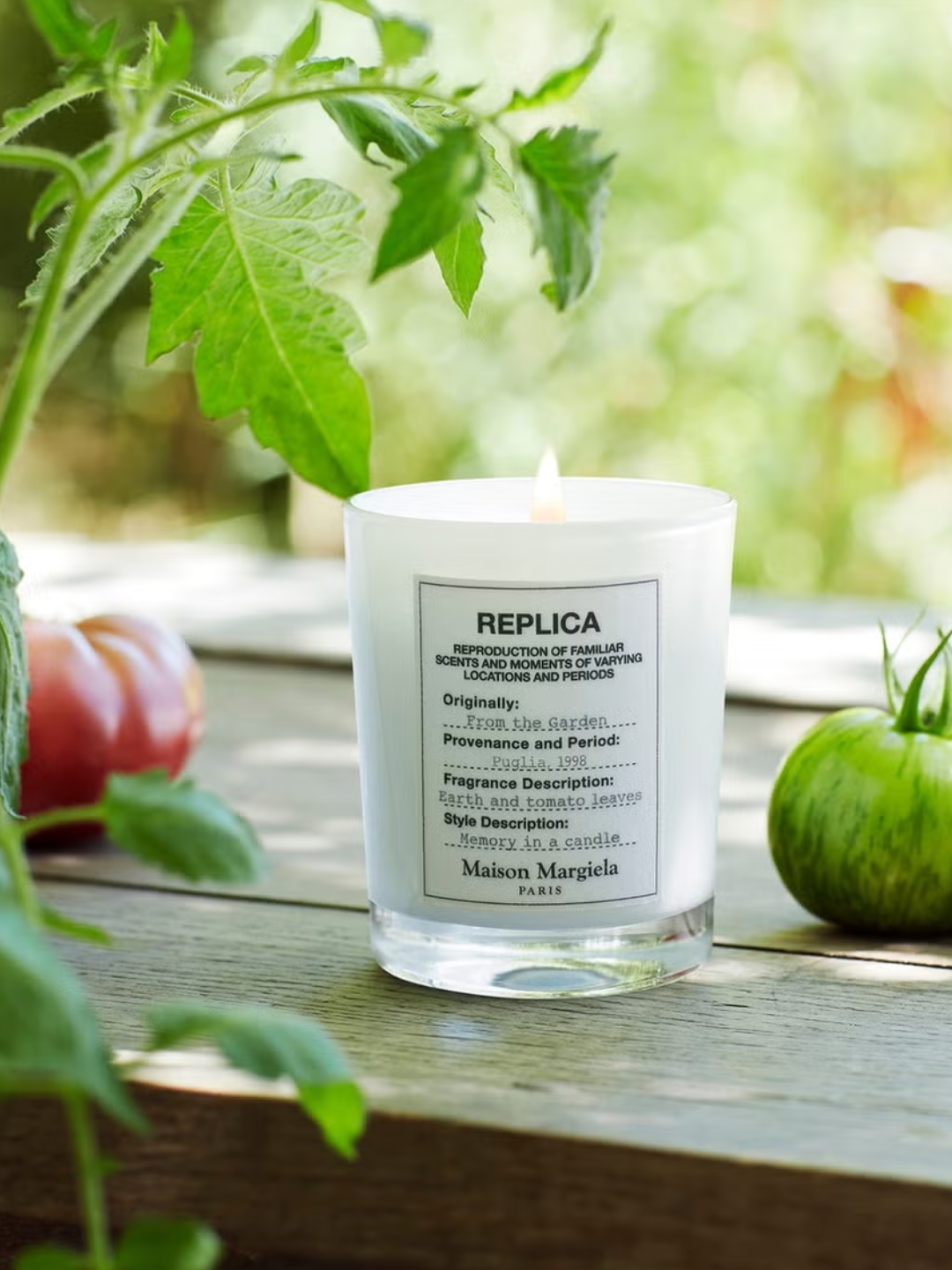 A glass candle from Maison Margiela beside tomatoes