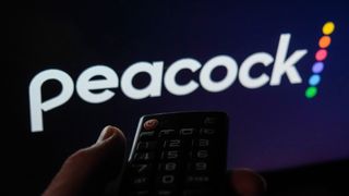 Remote held up to screen with Peacock TV logo