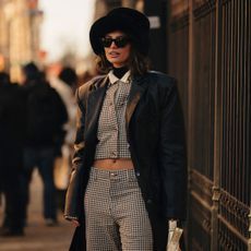 A guest at New York fashion week wearing a fur hat, houndstooth suit and leather coat, the perfect outfit for a smoky perfume