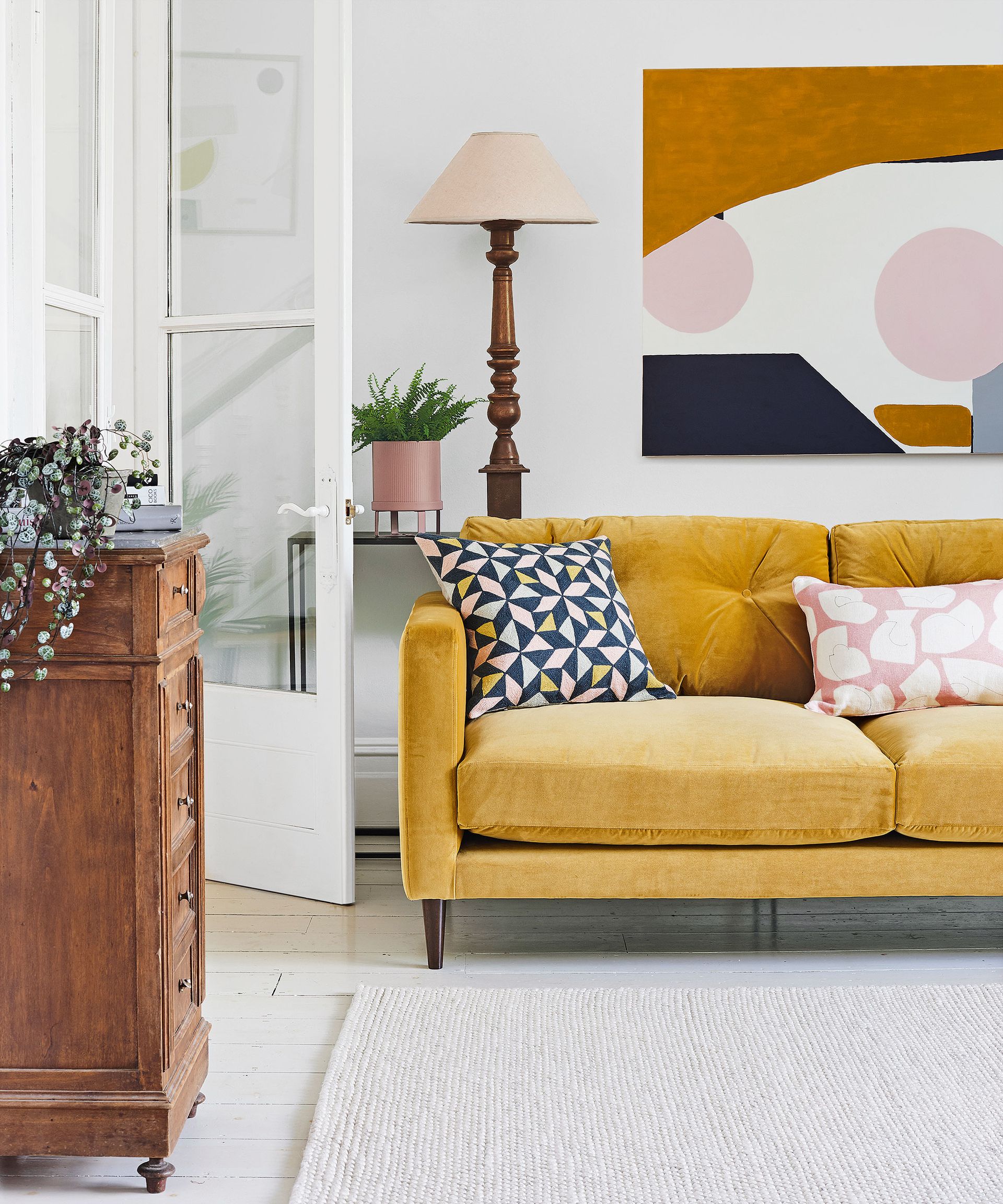 living room with yellow sofa white walls and floor abstract art painting hung on wall