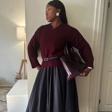 Influencer @nnennaechem wears a v-neck burgundy jumper with a black balloon skirt and mesh ballet flats.