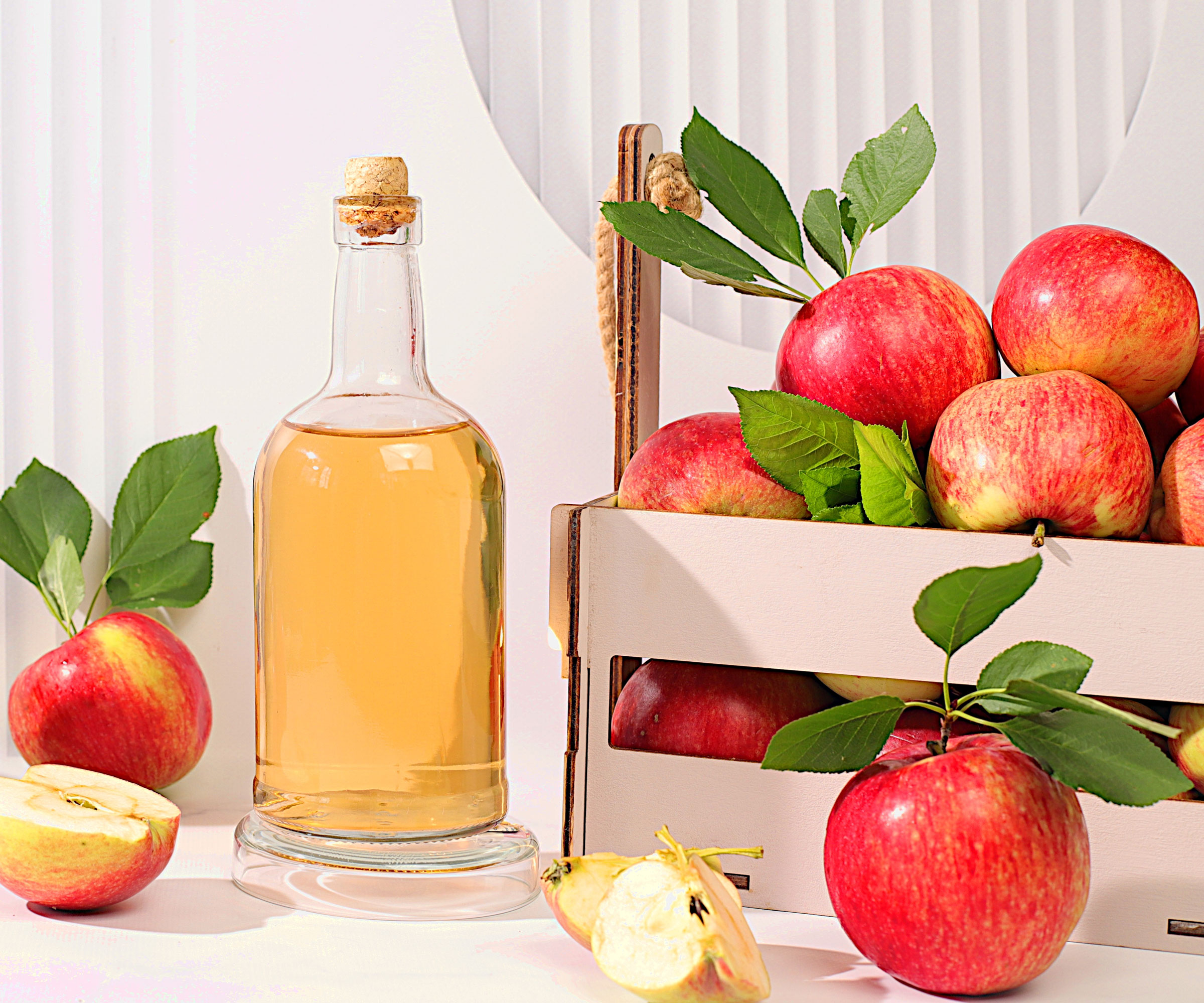 red apples in crate and bottle of apple cider vinegar