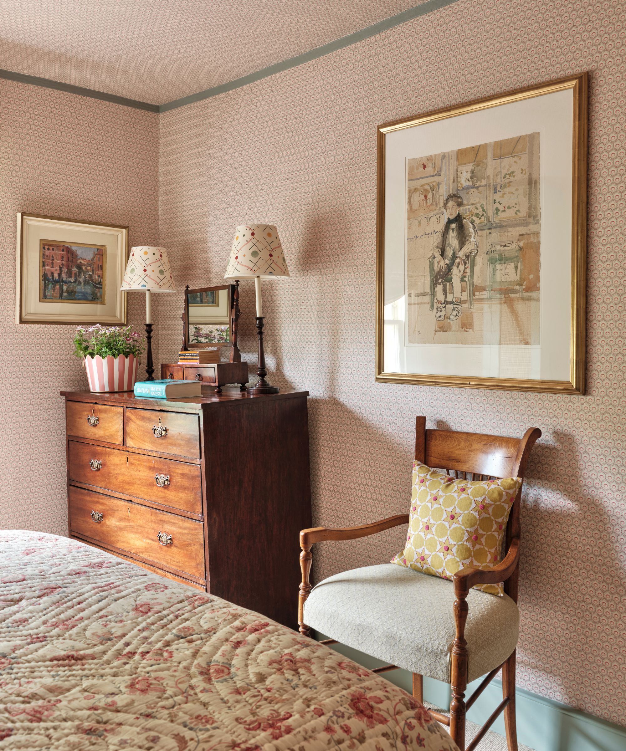 Vintage bedroom with antique wood chair, antique dresser, vintage drawing in gold frame, floral quilt on bed