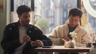 Scott (Francois Arnaud) and Shane (Hudson Williams) sitting at a table in Heated RIvalry