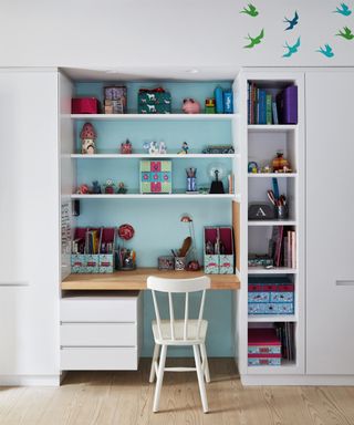 A child's bedroom with a recessed desk area picked out in pale blue paint against white surroundings.