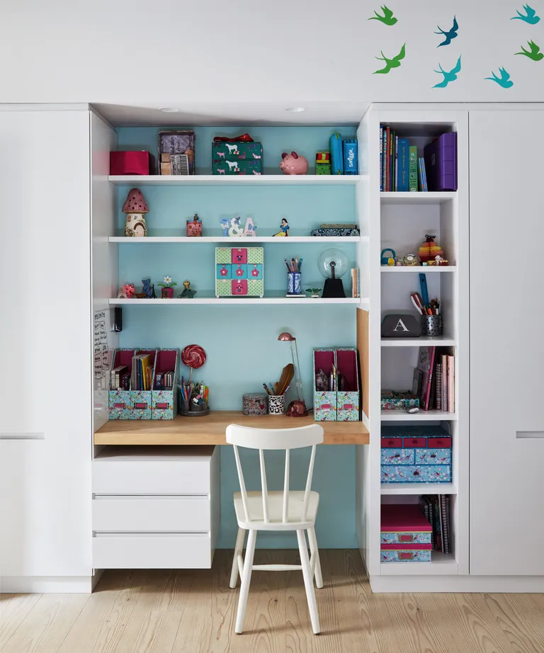 A child's bedroom with a recessed desk area picked out in pale blue paint against white surroundings