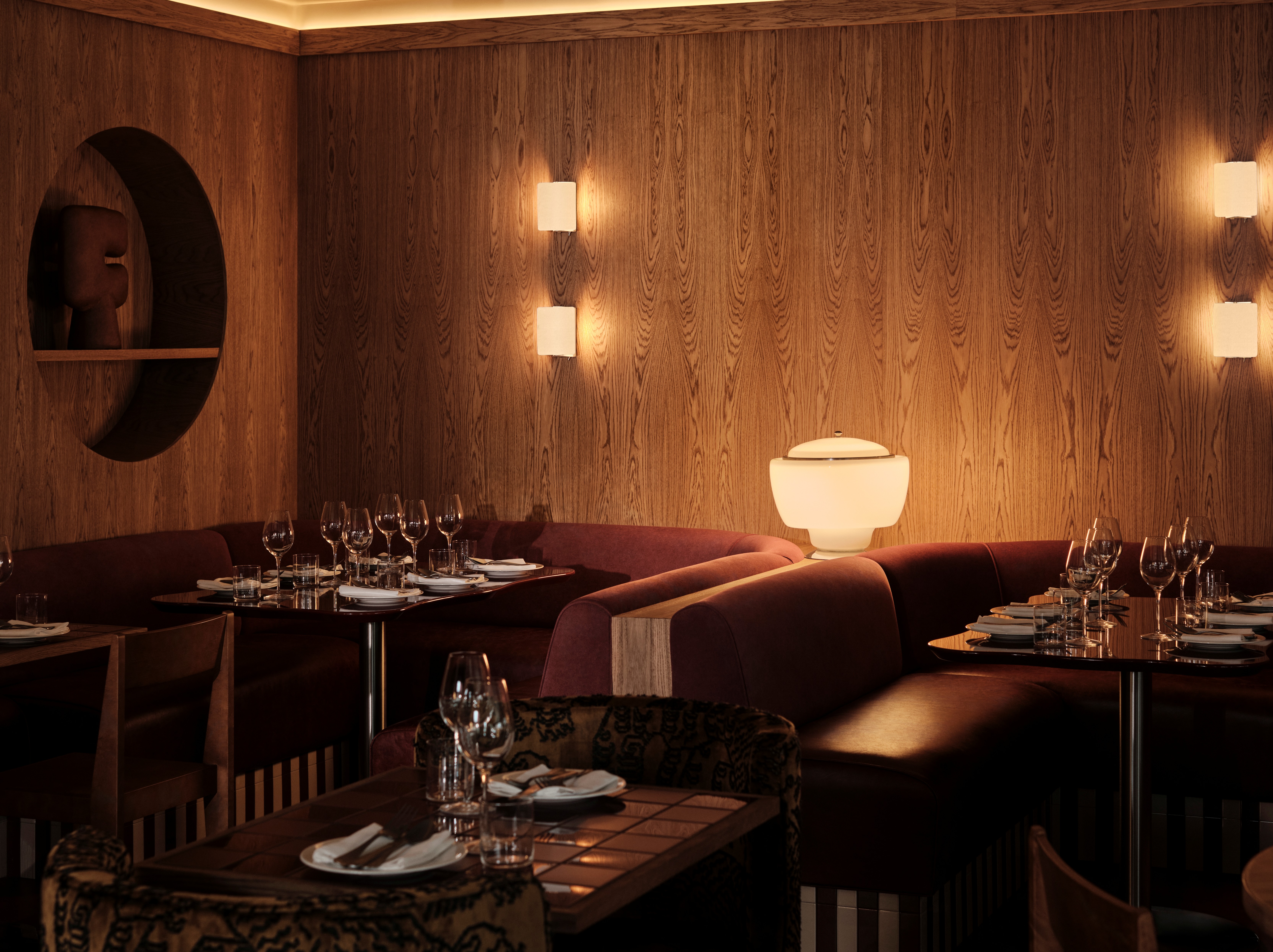 Interior shots of a restaurant with wooden surfaces, warm, sculptural lighting, lacquered and tiled surfaces, and a retro-inspired ambiance.