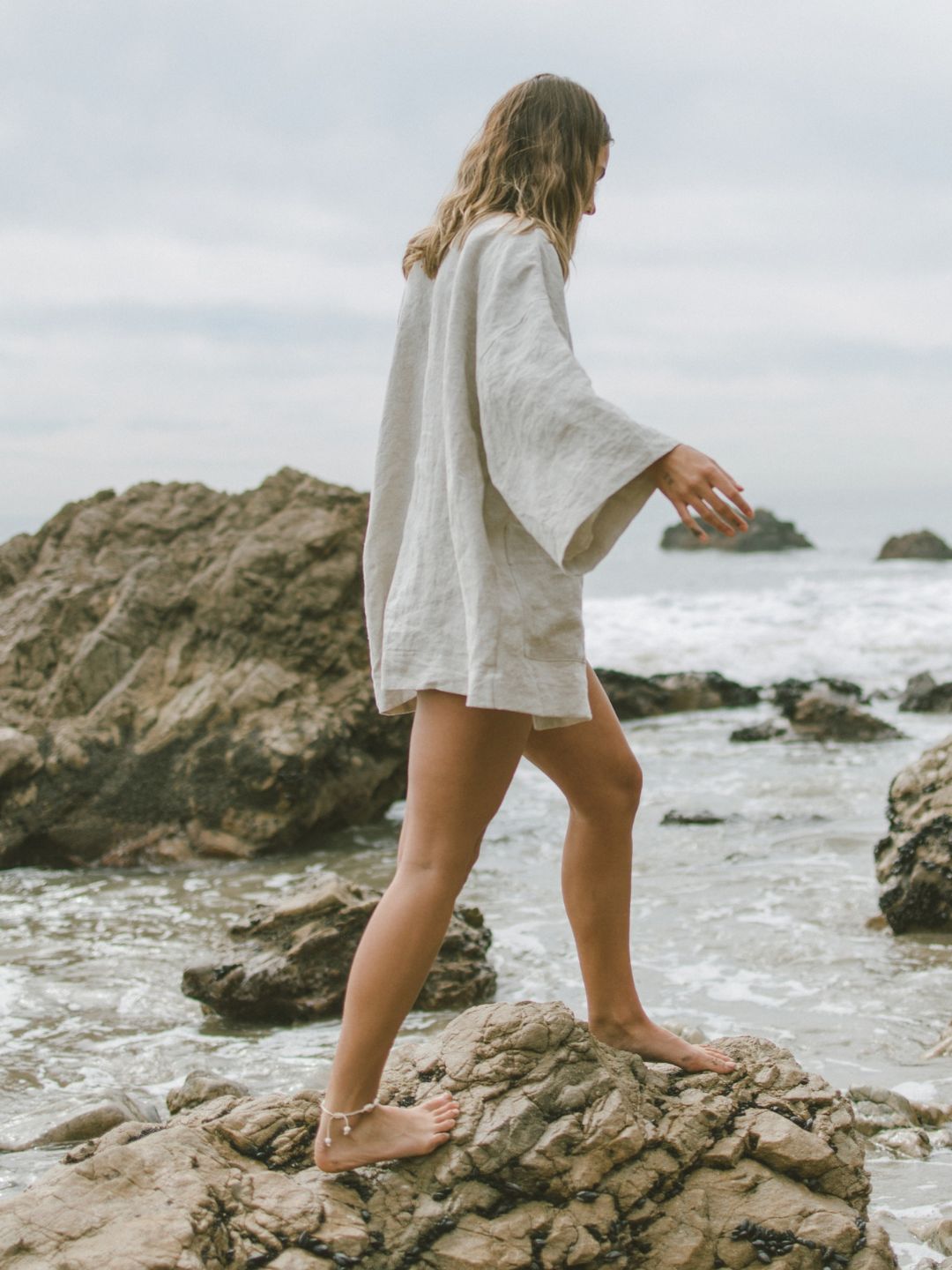A woman meditating, on the beach, and by the ocean