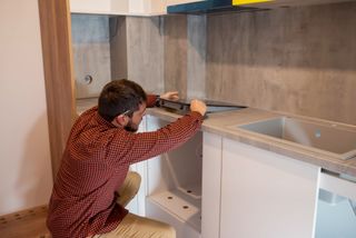 a worker fitting a kitchen with an induction hob