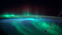 A green aurora over the blue of the ocean