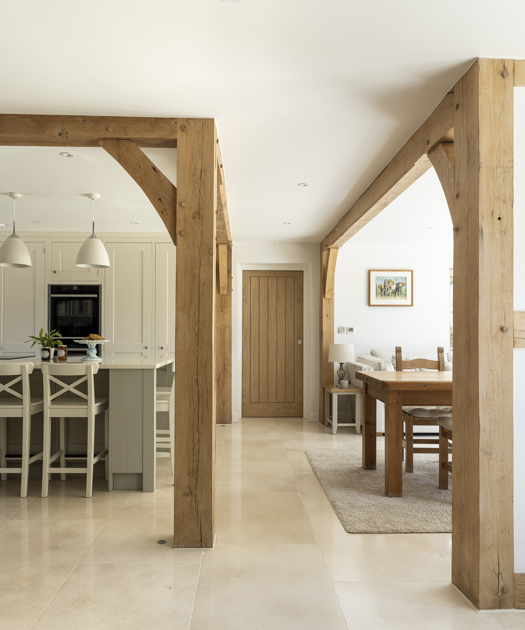 An open plan downstairs in a farmhouse style new build home with exposed timber beams and posts and light interiors