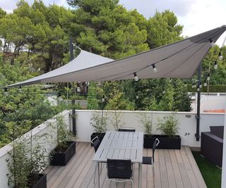 white shade sail over a balcony dining area