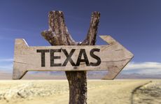 Wooden arrow sign that reads "Texas" against a desert backdrop