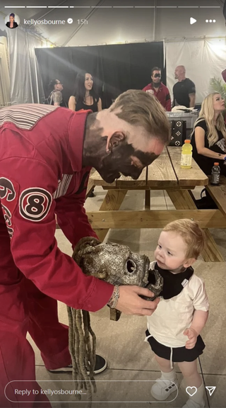 Corey Taylor gives mask to a child, with an unmasked Slipknot member behind