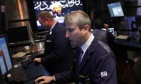 News of Osama bin Laden&amp;#039;s death flashes on the screen behind New York Stock Exchange traders: The al Qaeda leader&amp;#039;s death could ease tensions in the oil-rich Middle East, say some commentator