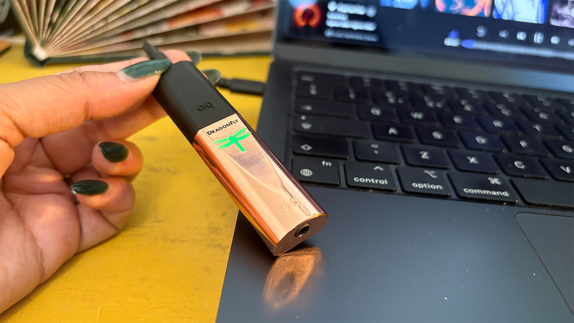 AudioQuest DragonFly Copper DAC held in hand and resting on laptop