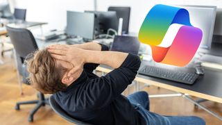 Mid adult businessman covers his face with his hands while seated at his desk, expressing a moment of stress or contemplation in a startup office paired with the Microsoft Copilot AI logo