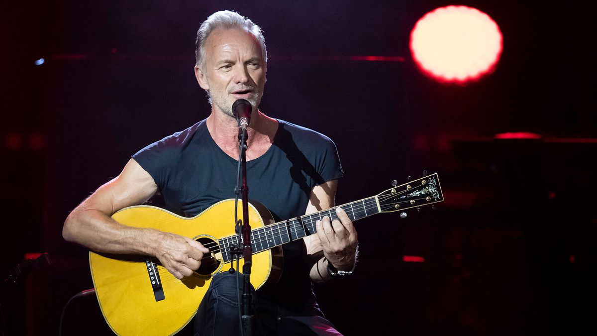 Sting performing onstage with an acoustic guitar