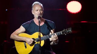 Sting performing onstage with an acoustic guitar