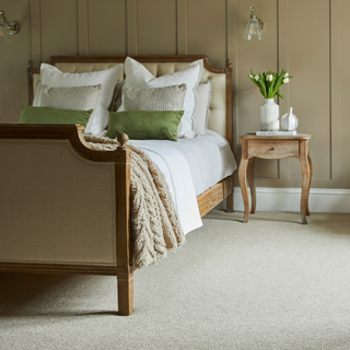 a neutrally decoarted bedroom with beige wool carpet on floor and wooden bed