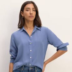 A woman wearing a dusky blue shirt and jeans from Everlane.
