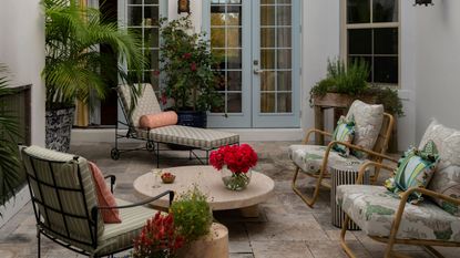 a large courtyard patio area with blue painted french doors and floral and stripe vintage style patio furniture