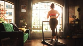 A photo of a woman exercising on a treadmill at home