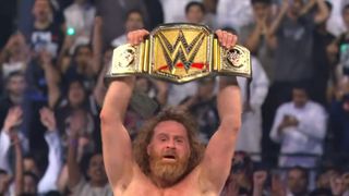 Sami Zayn celebrates after winning the WWE Championship by raising the belt in the air.