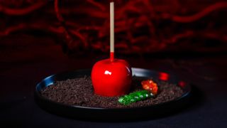 The Poison Apple shown plated, on a black table, in front of a red curtain for Universal Halloween Horror Nights 33.