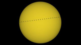 The International Space Station transiting the sun. Multiple images of the ISS spread across the solar surface like a line of ants crossing the screen.