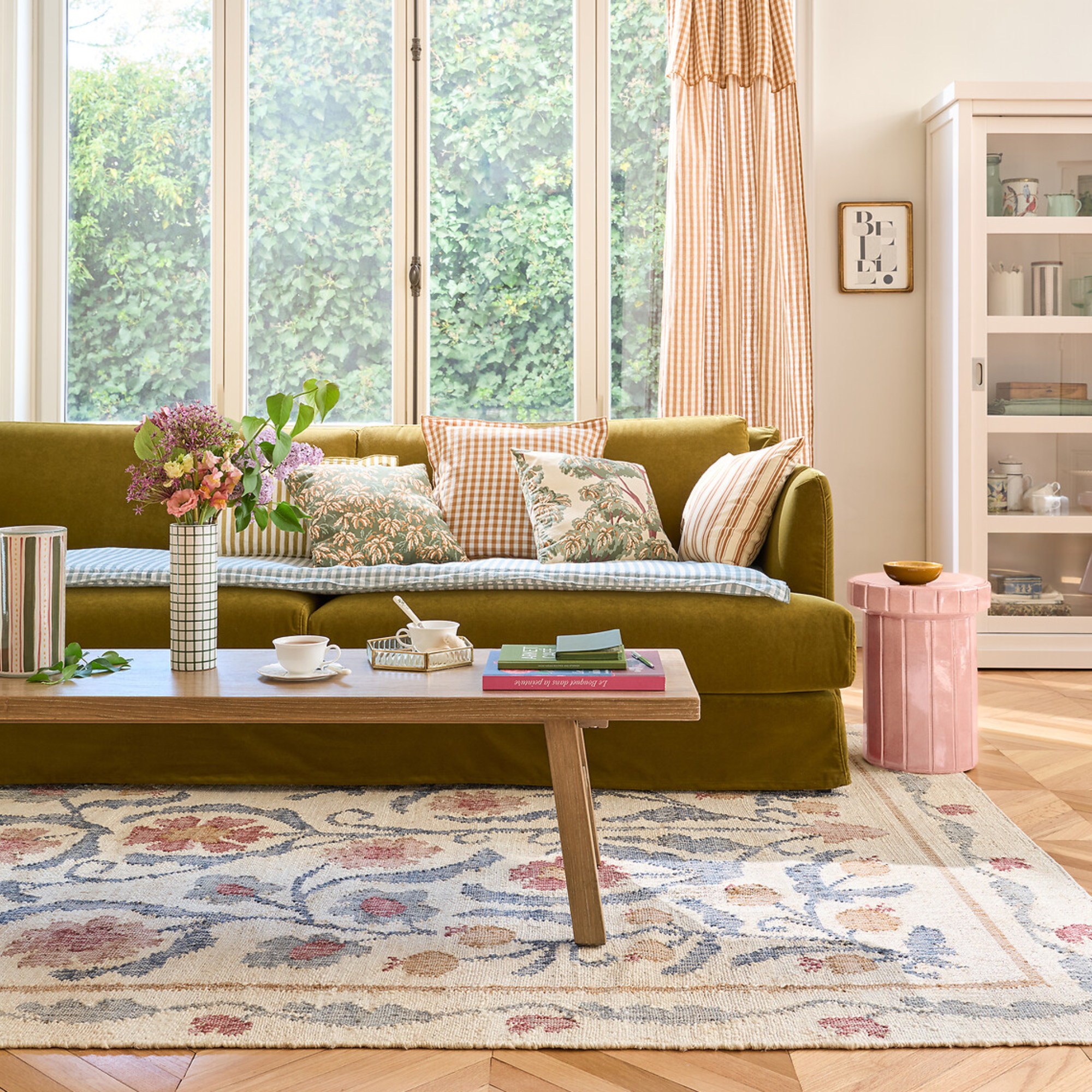 living room with green sofa and floral rug with wooden coffee table
