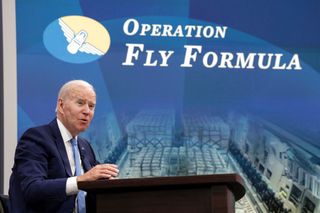 President Joe Biden next to a powerpoint presentation of Operation Fly Florida