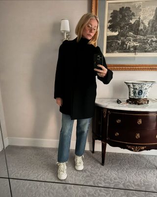 Gwyneth Paltrow wears a black turtleneck sweater, blue jeans, and white sneakers.