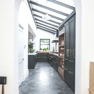 galley kitchen with white walls dark cabinetry and tiled floor and glazed roof