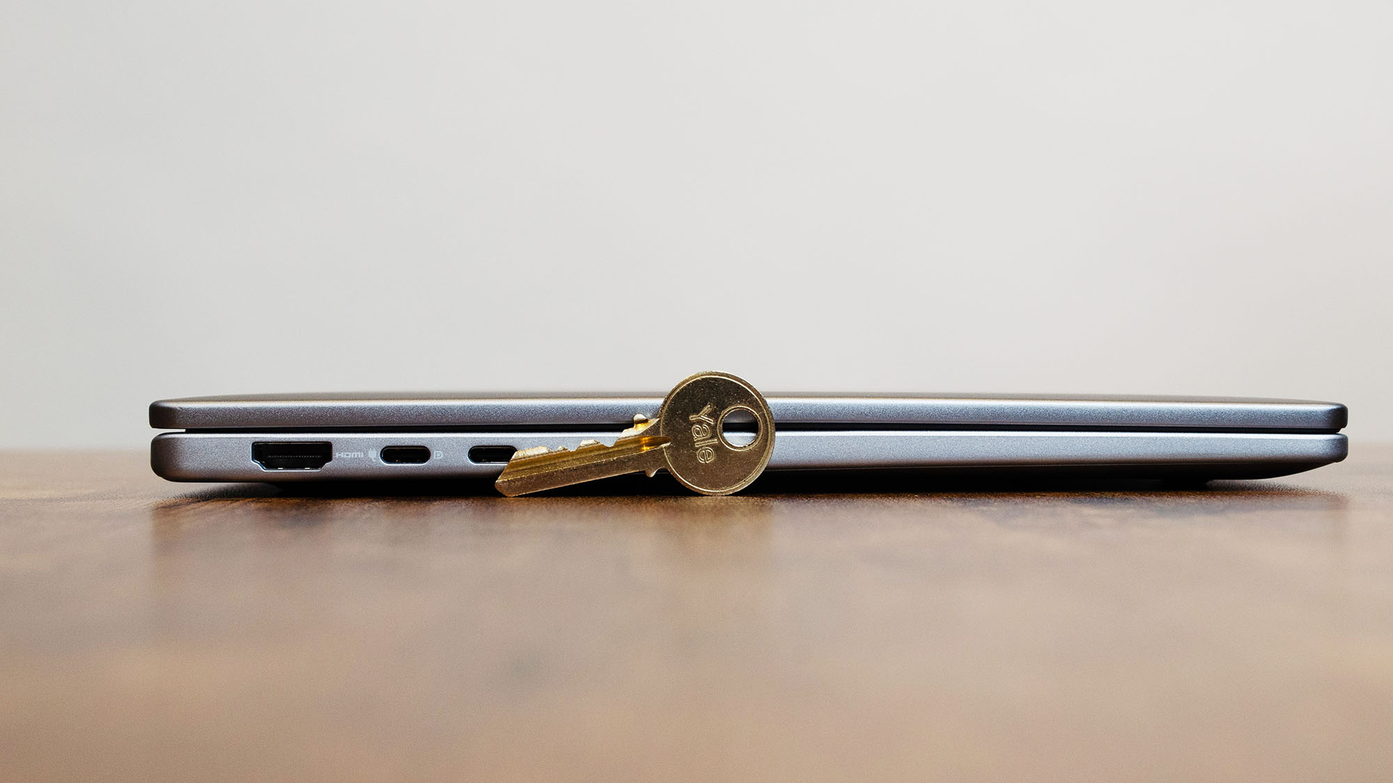 A Dell 14 Plus on a desk in front of a house key to demonstrate its thinness