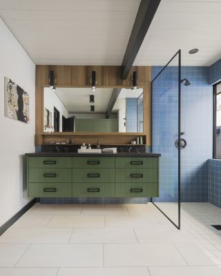 Khaki green bathroom cabinet with mirror above it