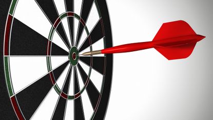 A red dart stuck in the bull's-eye of a black-and-white dartboard.