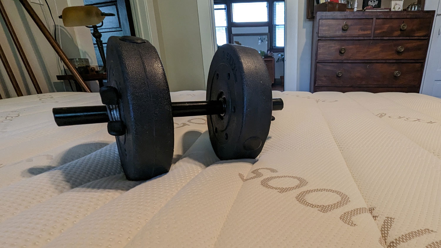 A dumbbell on the Saatva Memory Foam Hybrid mattress