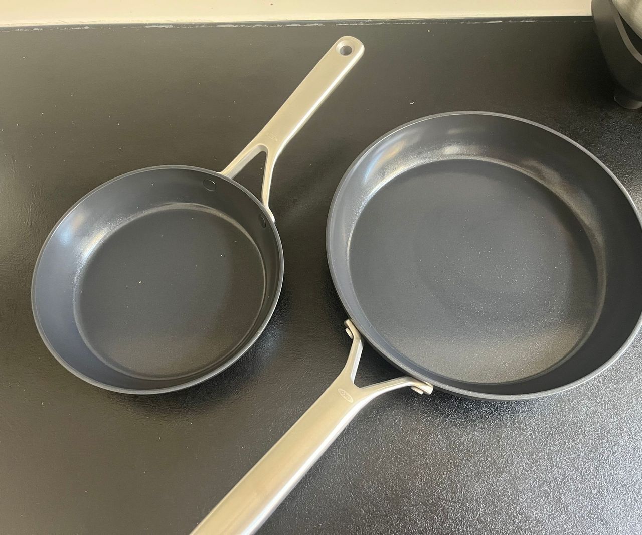Two black ceramic frying pans on a black countertop